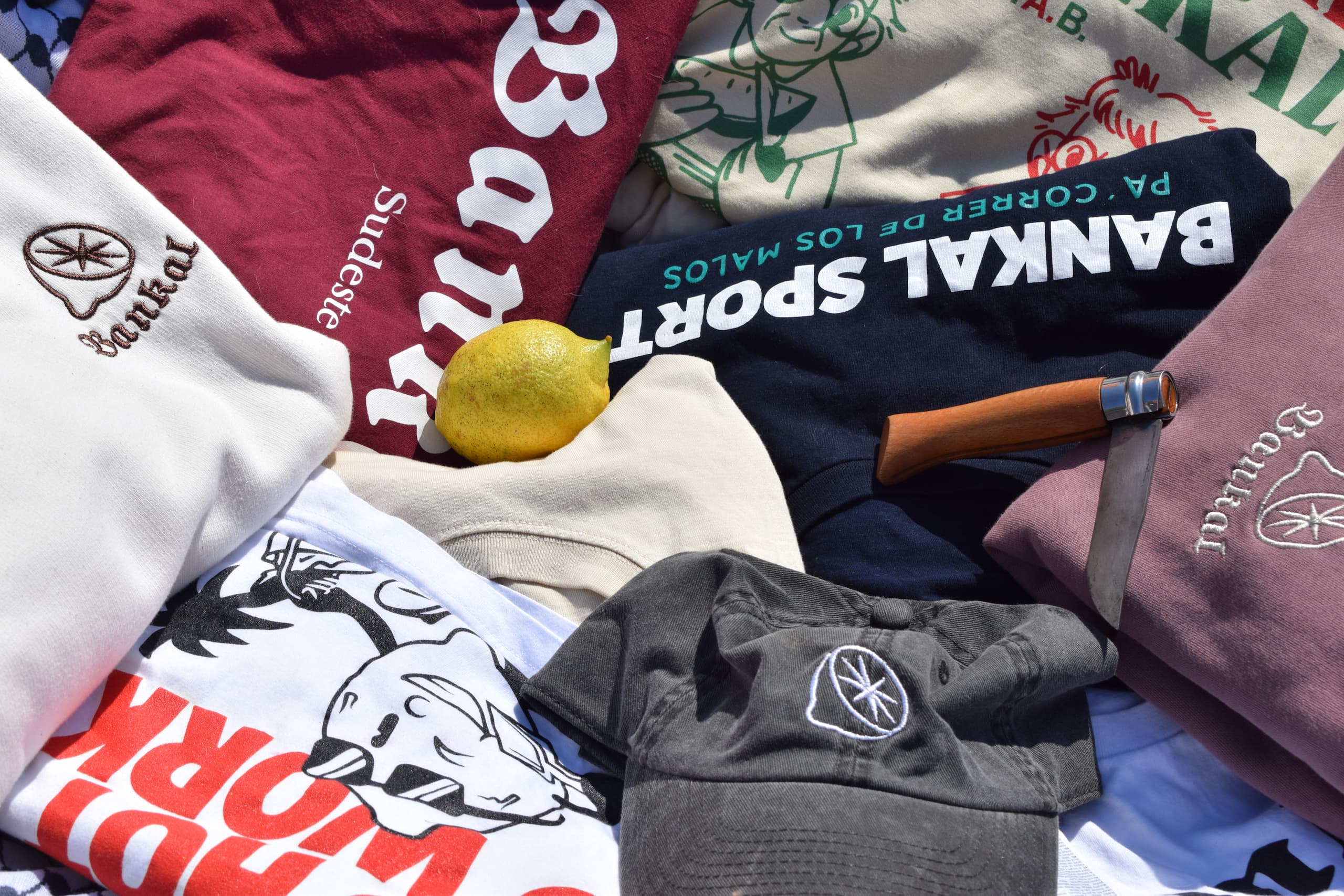 Prendas y gorras de Bankal Sudeste junto a un limón.